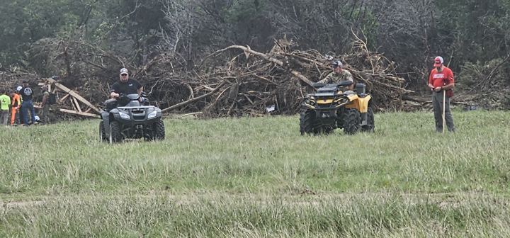 ATVs haul debris across a grass field