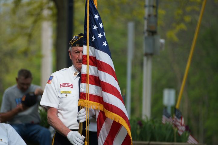 A veteran carries the American flag at a ceremony