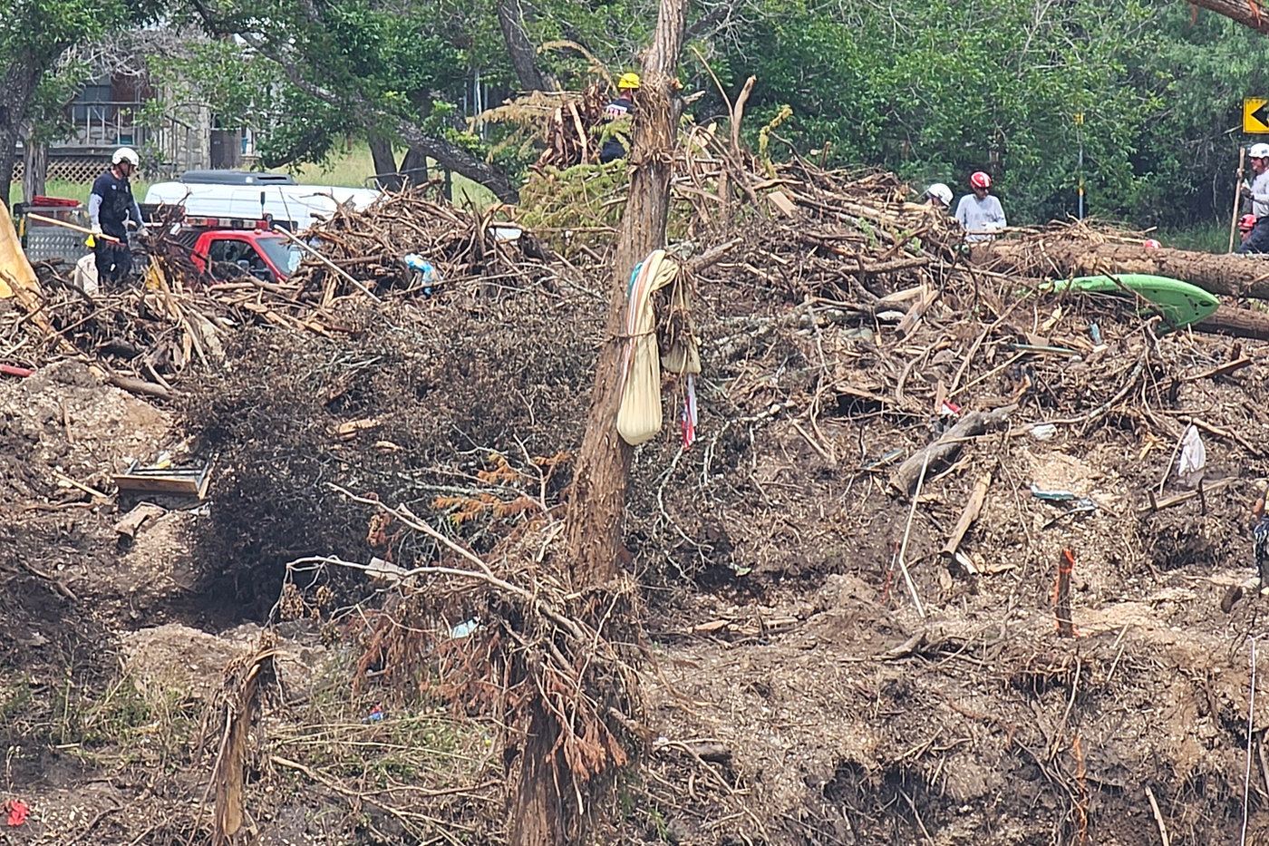 Volunteers work through flood debris among fallen trees