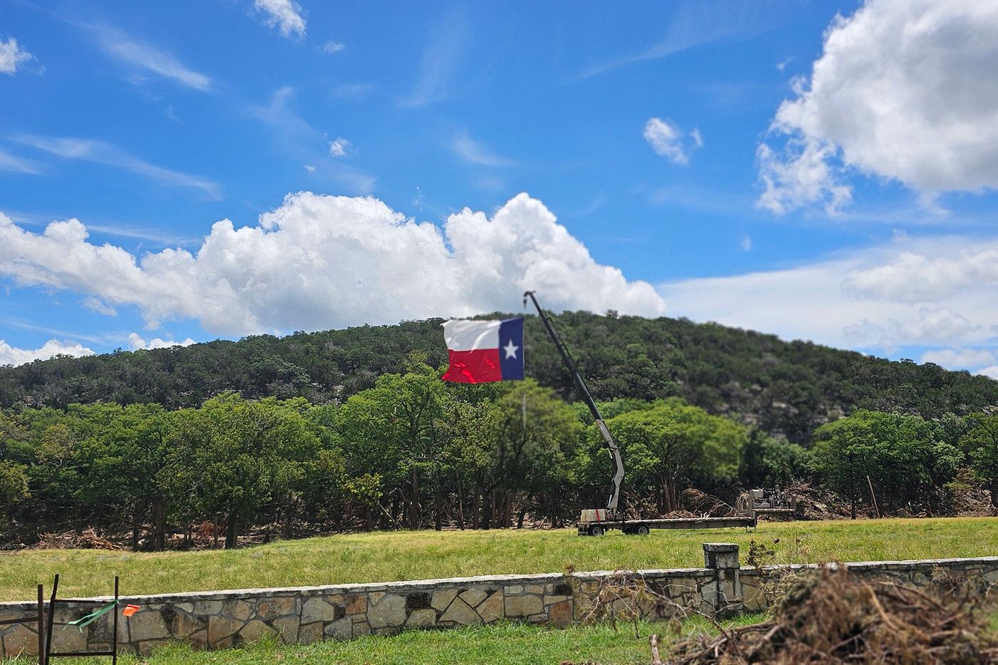 A Texas flag flies over a hillside after flooding